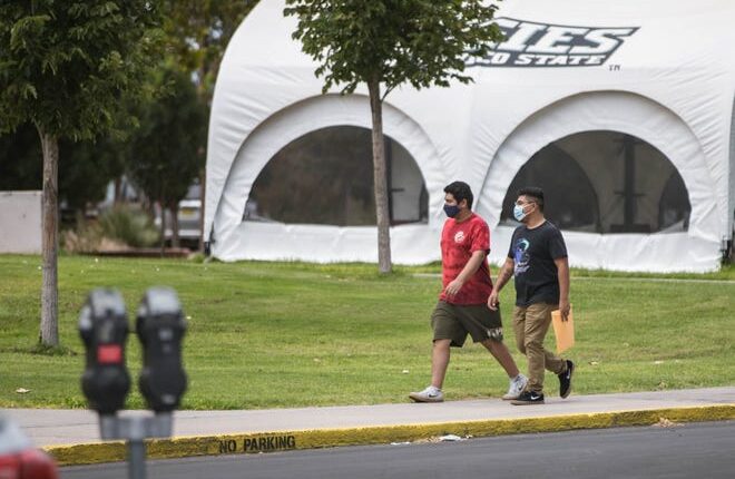 New Mexico state students wear masks while walking on the NMSU campus in Las Cruces on Wednesday, August 11, 2021.