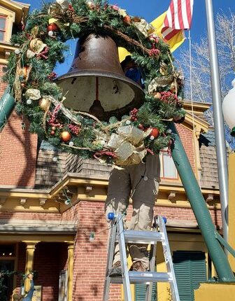 On Saturday, December 11 from 1-5, Victorian Christmas is back! Volunteer Eric Brown hangs a wreath on the bell in front of the museum.