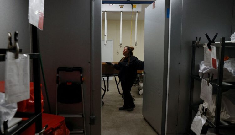 FILE PHOTO: Joanna Martinez, a funeral home worker, stands outside a refrigeration cooler with decedents who passed on due to the coronavirus disease (COVID-19) marked with red tags inside a refrigeration cooler with other bodies not affected at the Farmington Funeral Home in Farmington, New Mexico, U.S., December 14, 2021. REUTERS/Shannon Stapleton