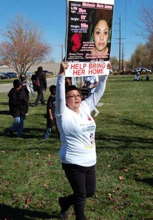 A participant in a walk and rally raising awareness about missing and murdered Indigenous people holds a sign on behalf of a missing woman on Nov. 13, 2021 at Berg Park in Farmington.