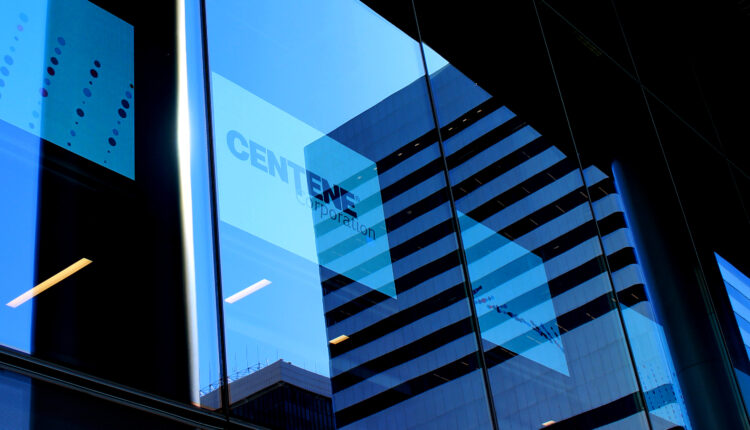 A photo shows Centene's logo on a TV screen inside an office building.