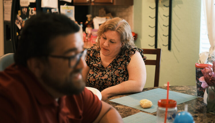 A photo of a woman and her husband sitting at home.