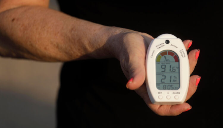 A photo of a woman holding a temperature and humidity reading device.