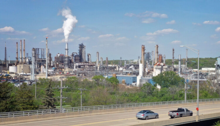 A stack emits a plume of white smoke from a refinery in Illinois near a busy interstate