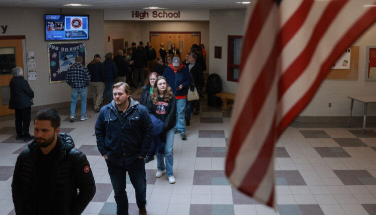 A photo of voters waiting in line to cast ballots indoors.