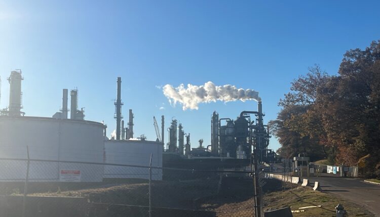 A smoke plume billows from an oil refinery