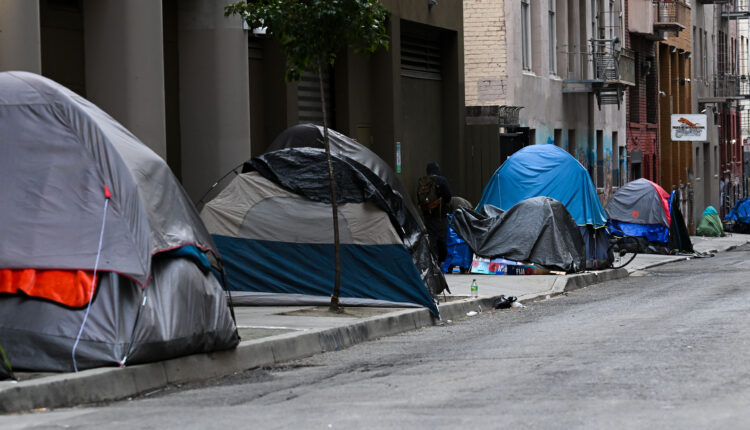 A photo of a row of tents set up in a homeless encampment.