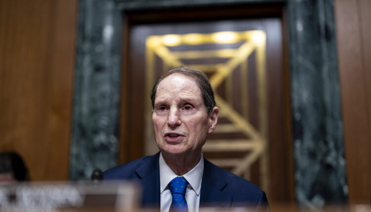 A man wearing a blue suit and blue tie speaks while seated at a table during a hearing in Washington, D.C.