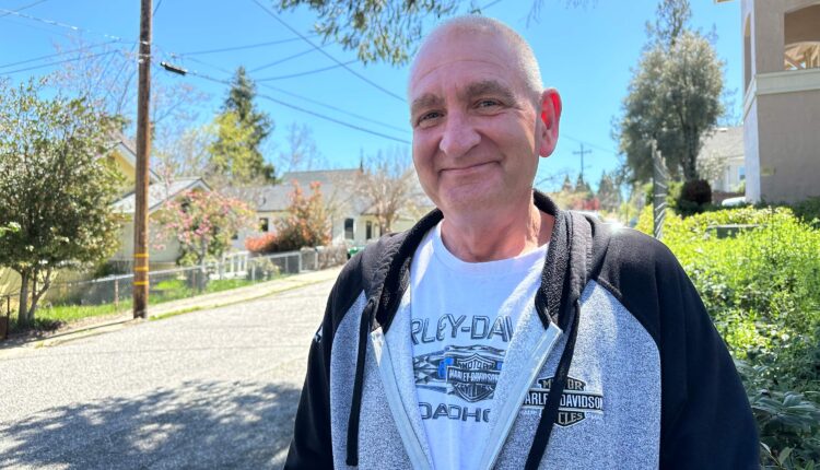 A photo of a man posing for a portrait outside.